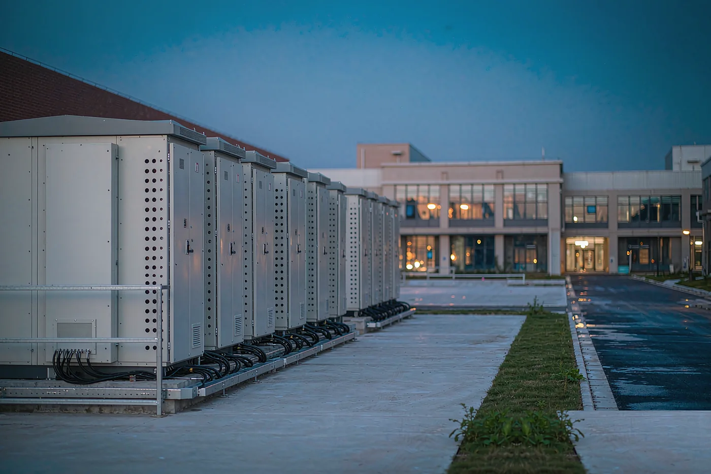 Outdoor commercial and industrial battery cabinets on a paved site at dusk